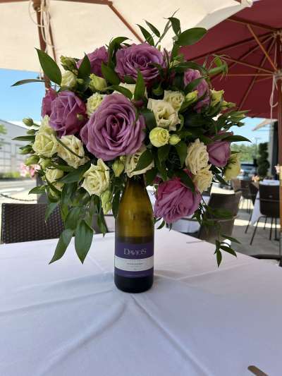 Flower arrangement in a Davio's wine bottle on a patio table at Davio's Lynnfield